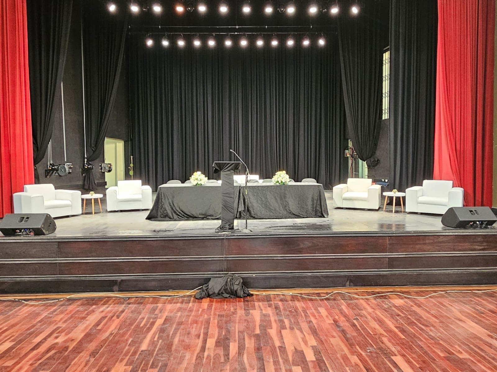 Theatre stage dressed with white lounge furniture and red curtains